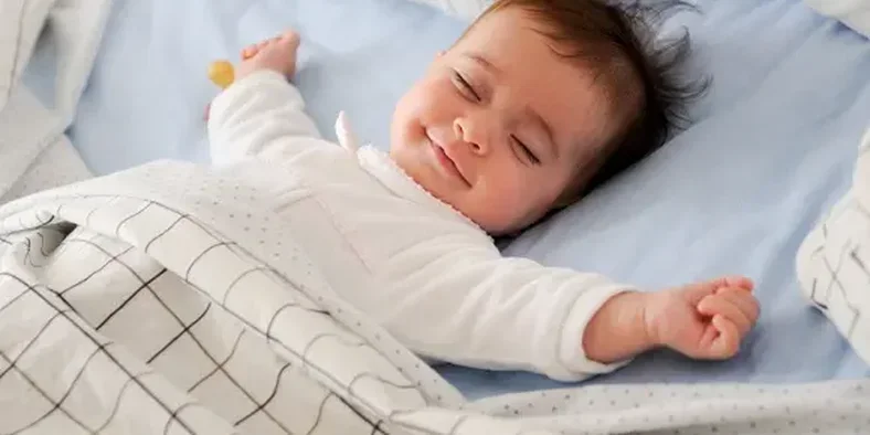 seorang bayi sedang tidur sambil tersenyum