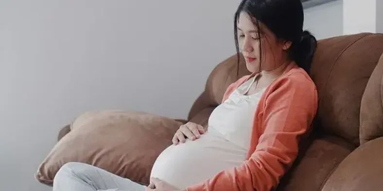 ibu hamil duduk di sofa