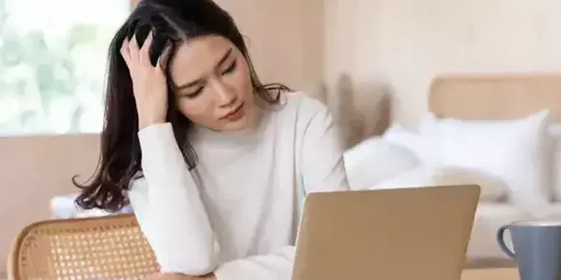 Pengusaha wanita memegang kepala sembari menatap laptop