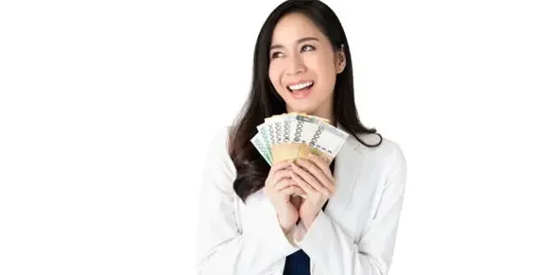 Seorang wanita memegang uang tersenyum bahagia