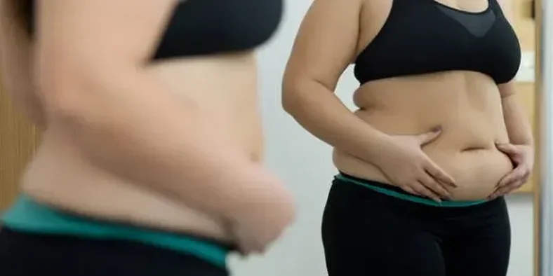 Wanita dengan perut buncit menghadap cermin