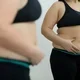 Wanita dengan perut buncit menghadap cermin