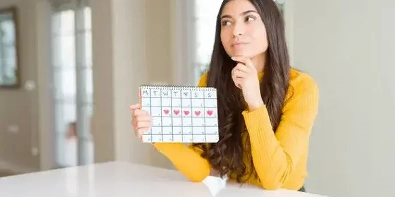 Perempuan sedang memegang kalender menstruasi