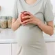 Ibu hamil memegang apel merah