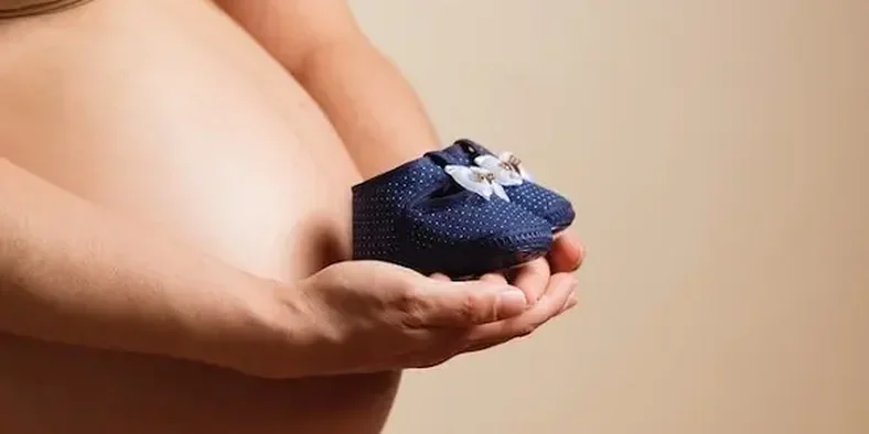 ibu hamil sedang memegang sepatu bayi