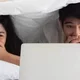 Wanita dan pria menonton film di ranjang