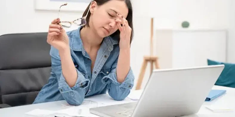 Wanita lelah bekerja di depan layar laptop