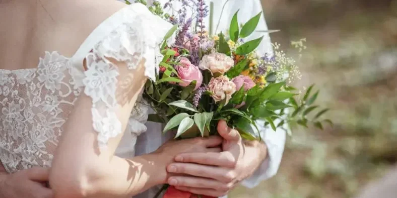 Pasangan menikah memegang bunga