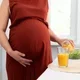 Ibu hamil menuangkan jus ke dalam gelas