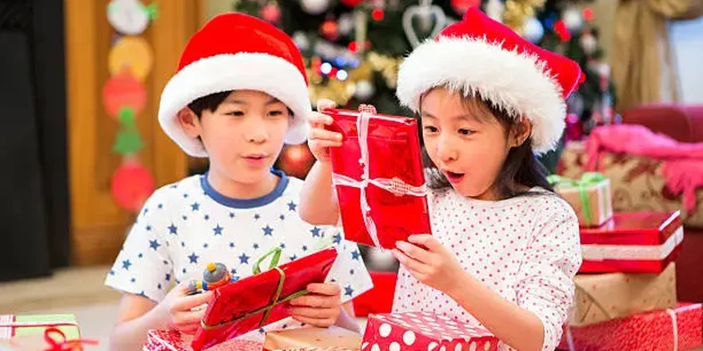 Dua anak sedang membuka kado natal