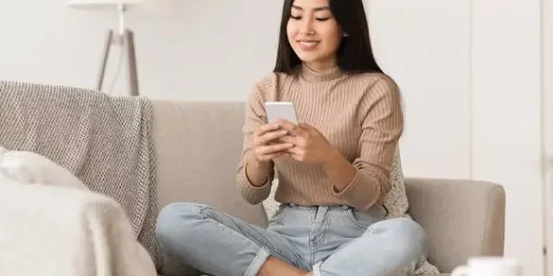 Wanita Asia sedang mengirim pesan lewat handphone