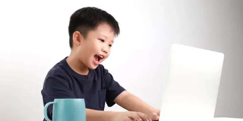Anak laki-laki sedang menggunakan laptop di rumah
