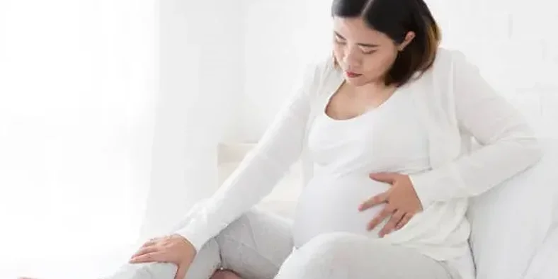 Ibu hamil memegang kaki yang bengkak