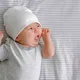 Bayi menggunakan topi putih tidur di atas kasur