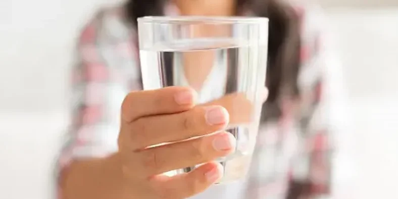 Wanita sedang memegang gelas air putih