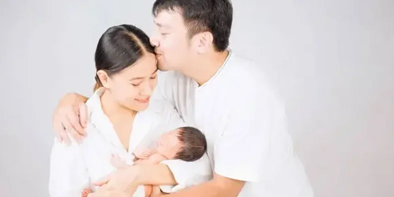 Suami mencium kening istri yang sedang menggendong bayi