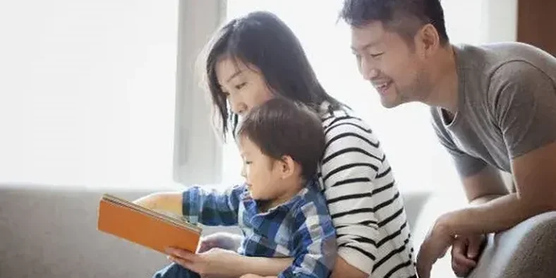 kedua orang tua membaca buku bersama anak
