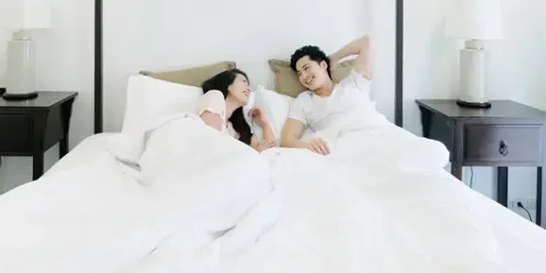 Pasangan suami istri bangun tidur dengan bahagia