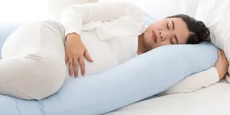 Ibu hamil tidur dengan posisi miring menggunakan bantal penopang