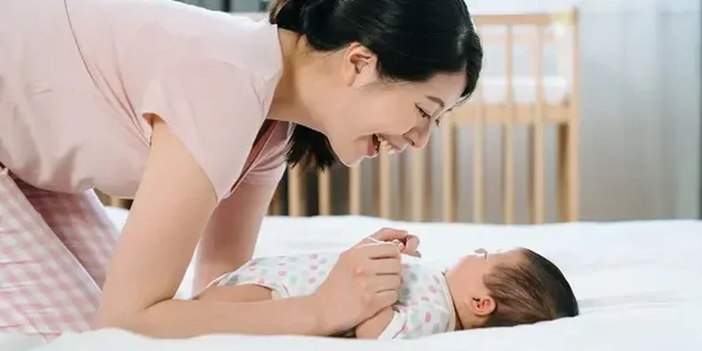 Seorang ibu sedang bercanda dengan anak bayi