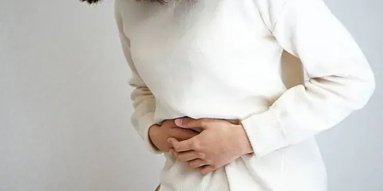 Seorang wanita sedang memegang perutnya yang sakit