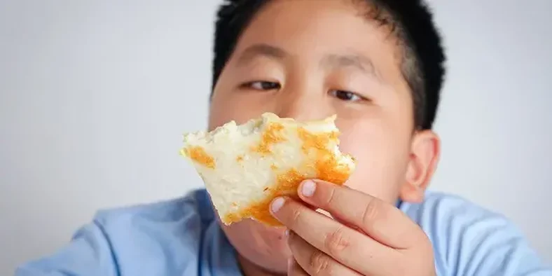 anak obesitas memegang roti