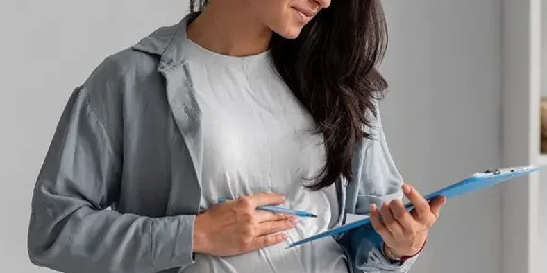 wanita hamil memegang pena dan papan buku